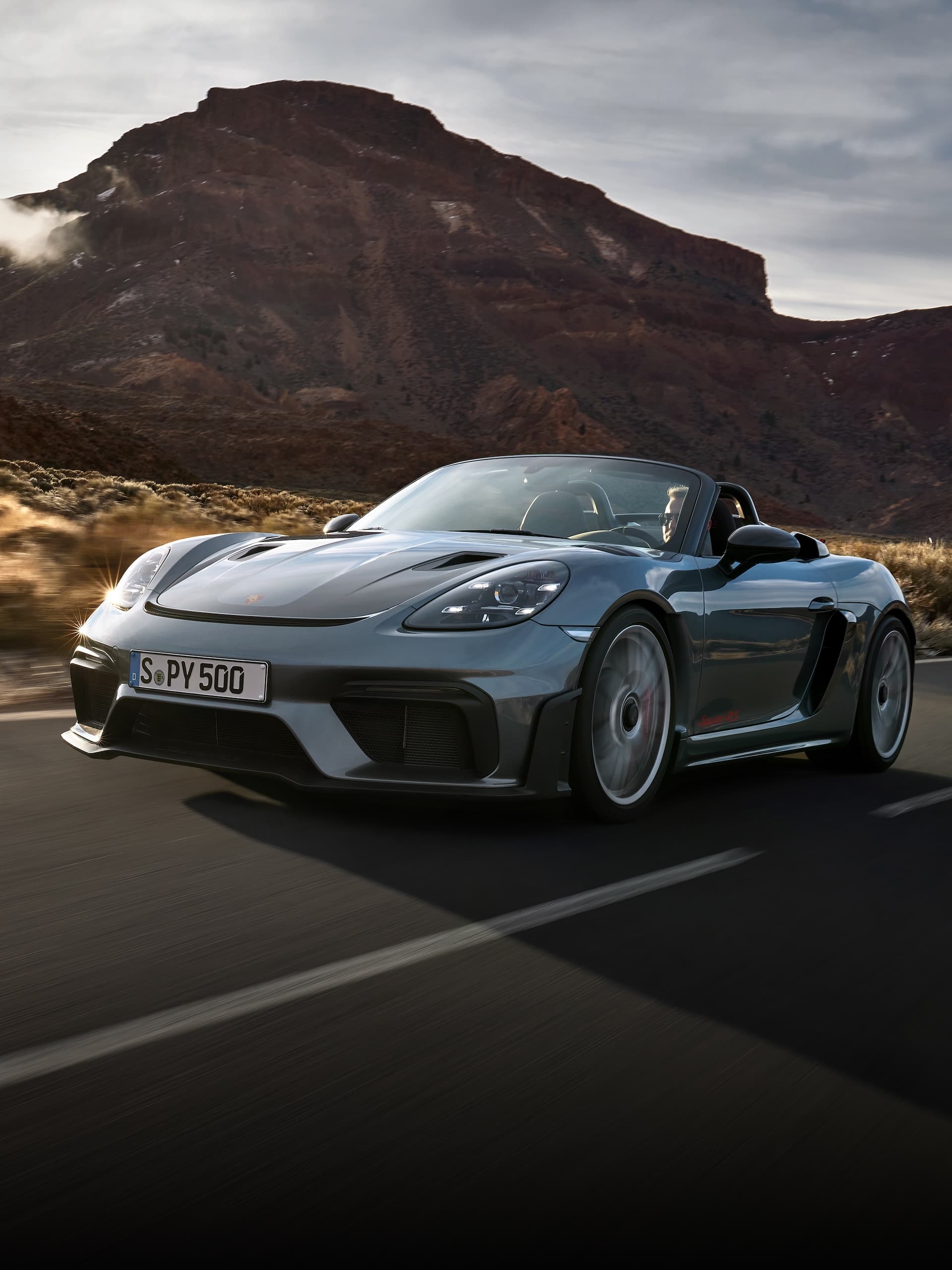Porsche 718 Spyder RS driving on the road between rock formations.